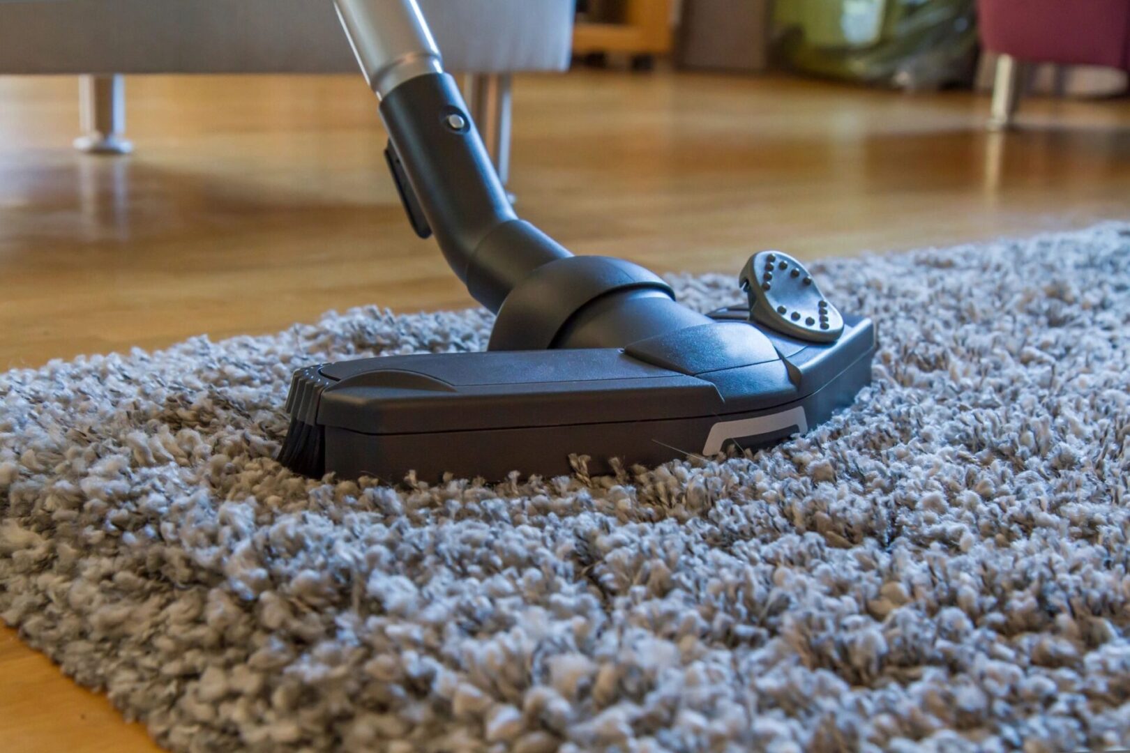 Vacuum cleaner cleaning a carpeted floor in a home setting.