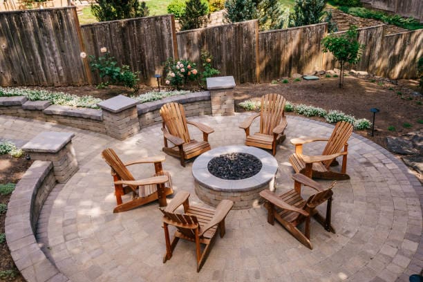Outdoor seating area with wooden chairs around a fire pit.