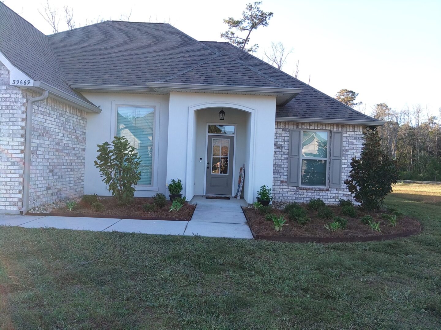 Front view of a single-story house with a porch and landscaped yard.