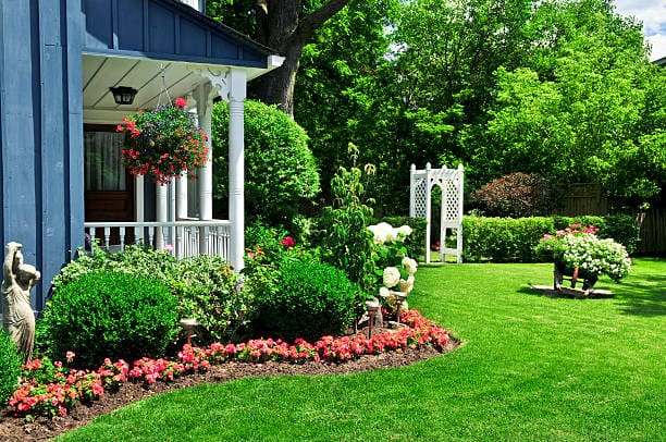 A lush garden with colorful flowers and a white porch.
