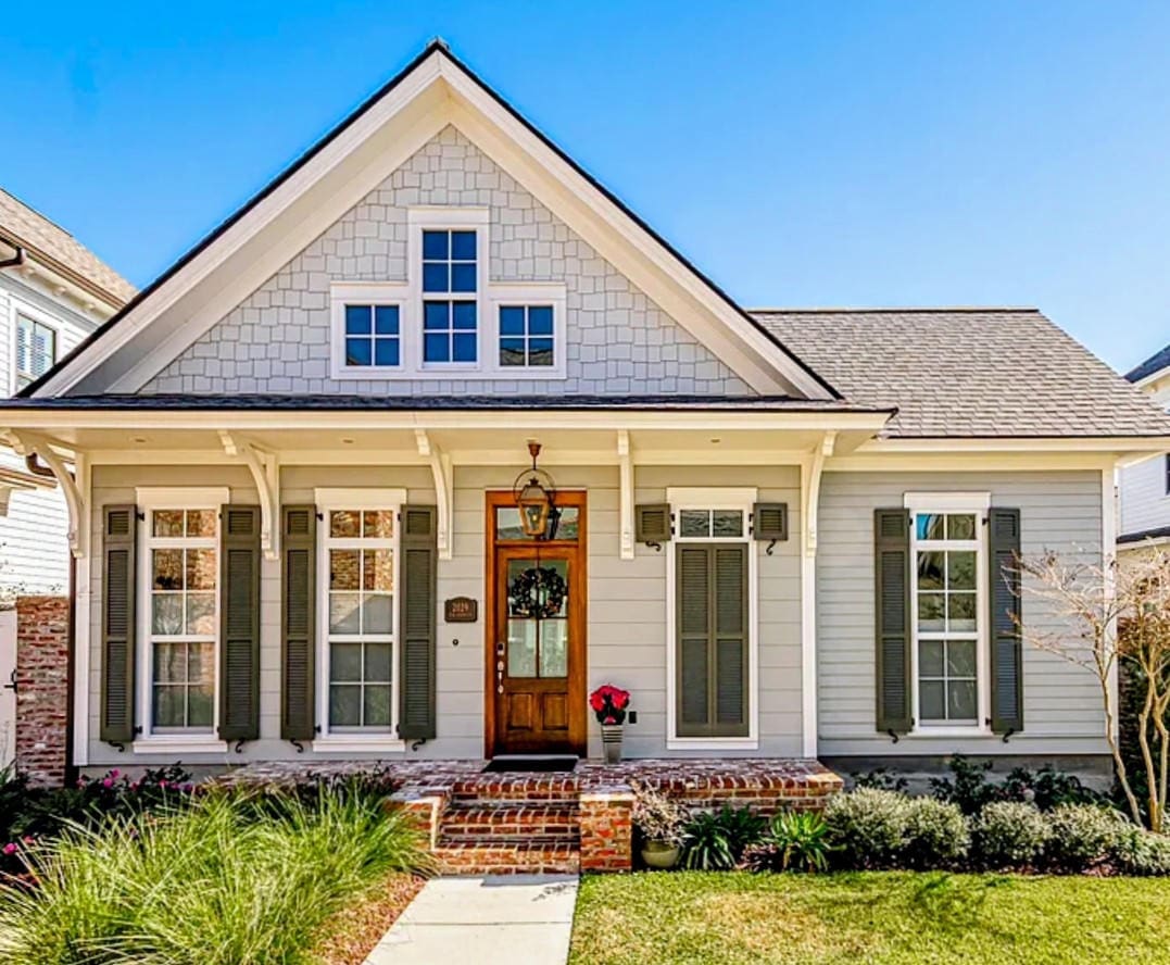 Charming white house with front porch and neatly landscaped garden.